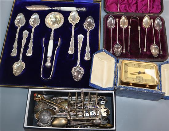 A silver toast rack, assorted silver and plated teaspoons and a bedside alarm timepiece